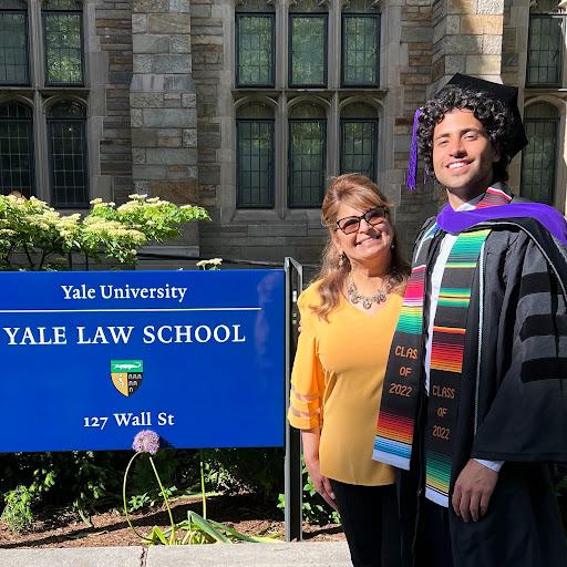 Manny Rutinel in cap and gown standing with his mother outside Yale Law School