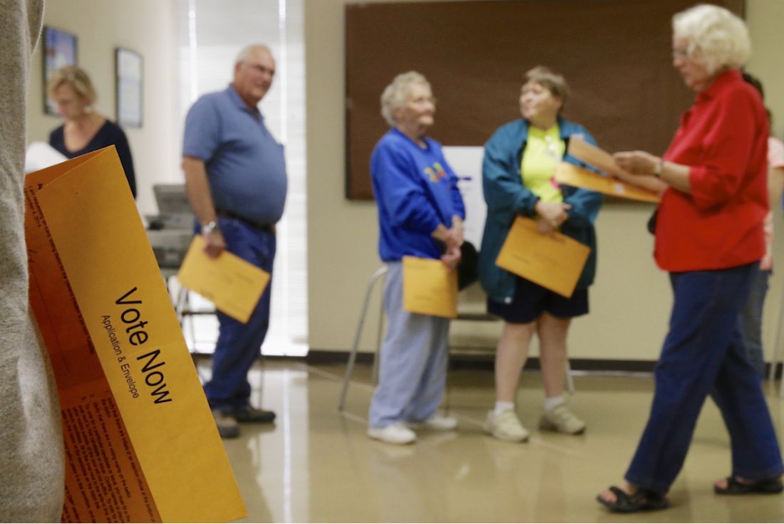 Nursing home residents and staff handling voting materials in a hallway